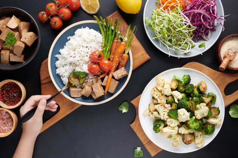 Top view female hands holding bowl with mixed vegetables salad young woman eating fresh salad meal vegetarian